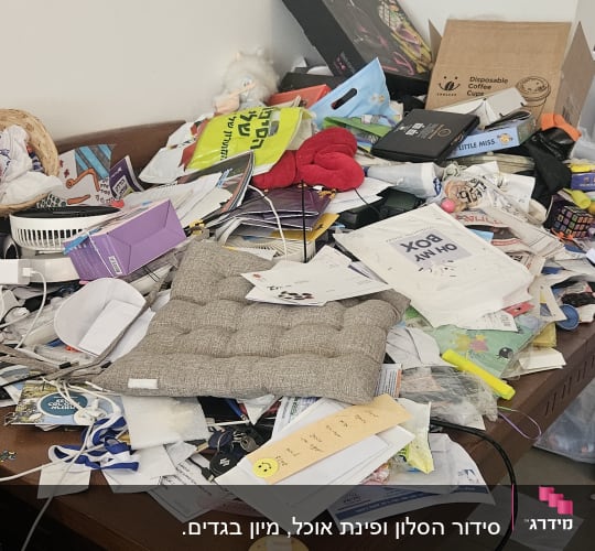 שולחן עמוס בניירות, קופסאות ופריטים שונים לא מאורגנים.